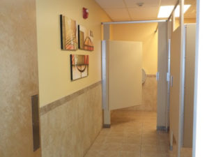 Restroom stall doors with decorative art on the wall outside stalls