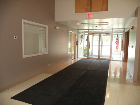 Community Center entranceway with front doors and floor mats. An American flag hangs outside the door.