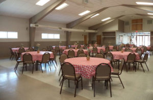 Community center with round tables decorated with checkered tablecloths and fresh flowers