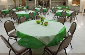Community center with decorated tables. Each table holds snacks and fresh flowers