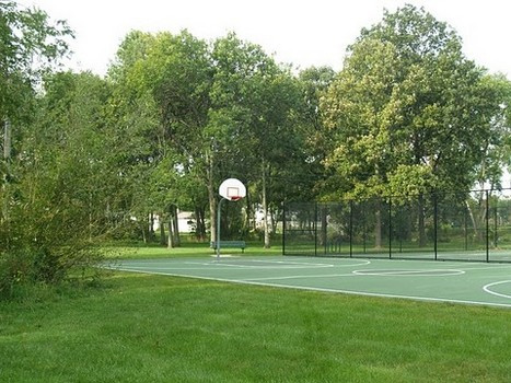 Basketball court next to park lawn and trees