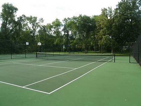 Tennis court next to basketball courts and surrounding trees