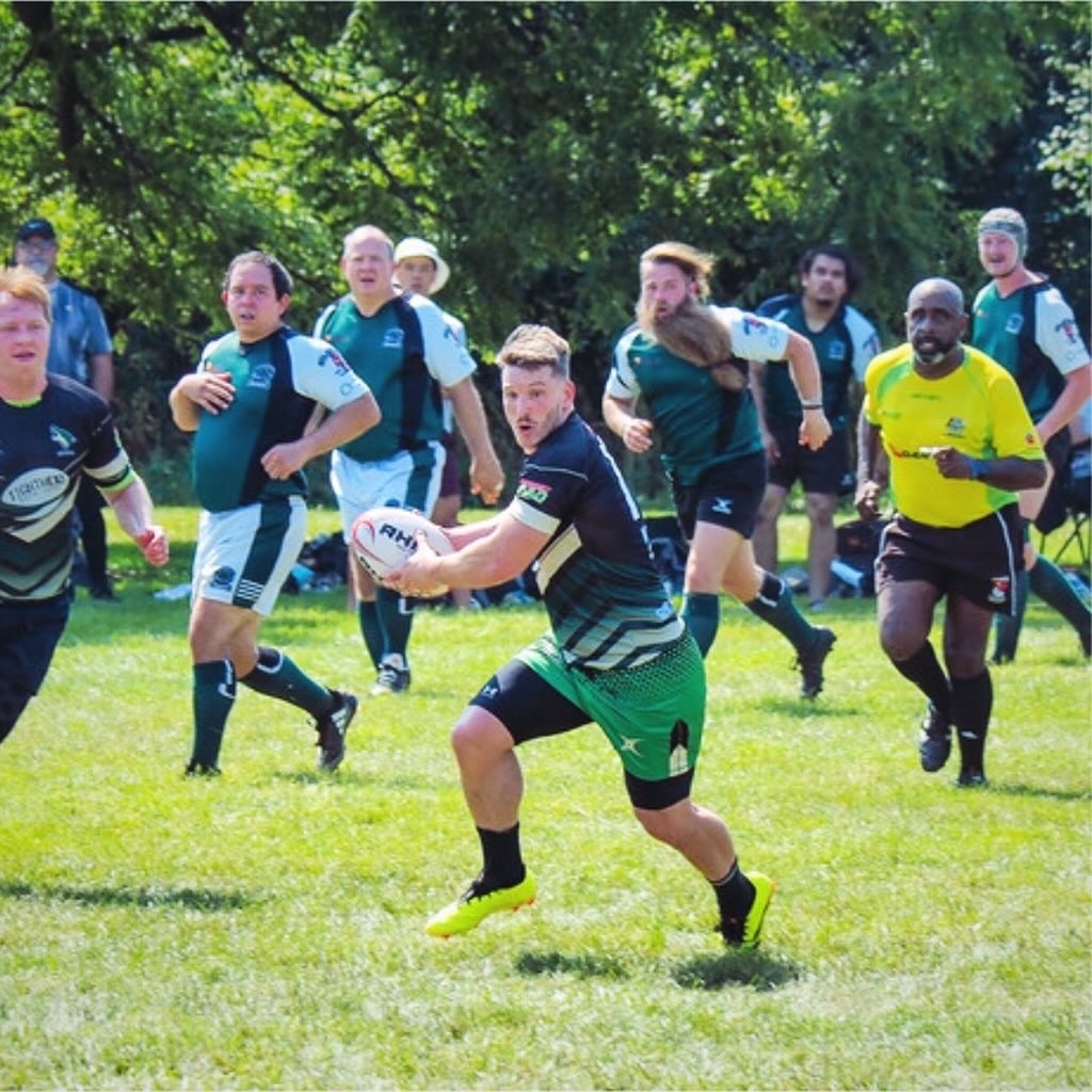 picture of a rugby player running with the ball with players from the other team running after him