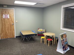 playroom with a couple tables and a bookshelf with books