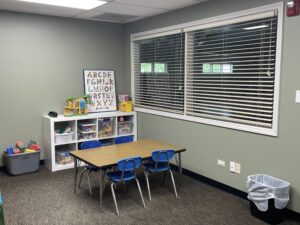 playroom with table and blue chairs and bookcase with toys in it