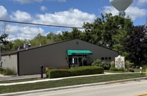 front of community center building with bushes plants and a sign