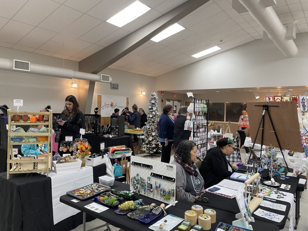 people sitting at tables selling crafts
