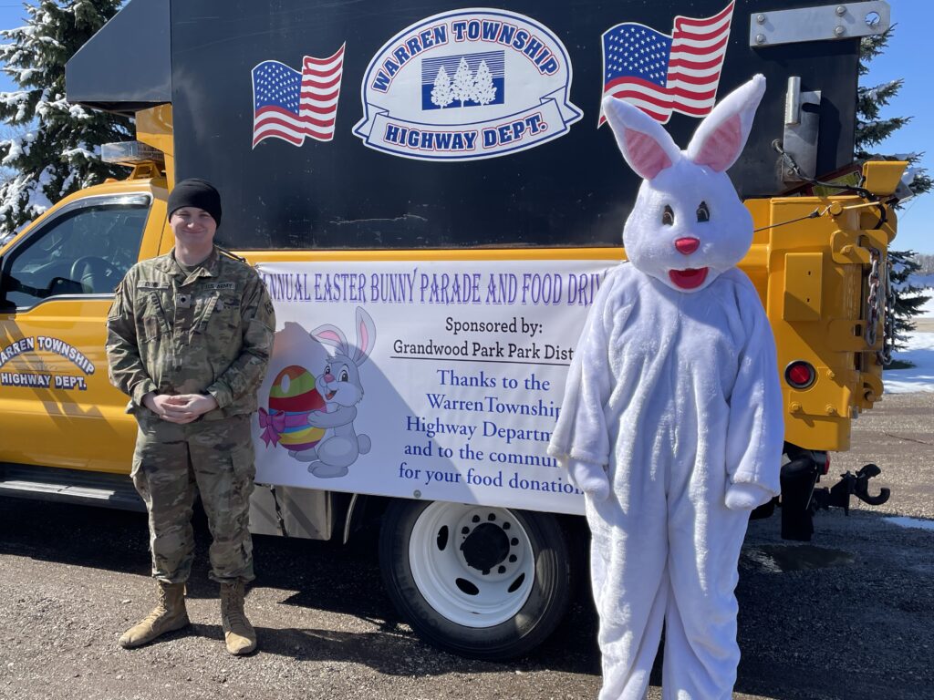 Easter bunny standing in front of a yellow truck with a banner on its side
