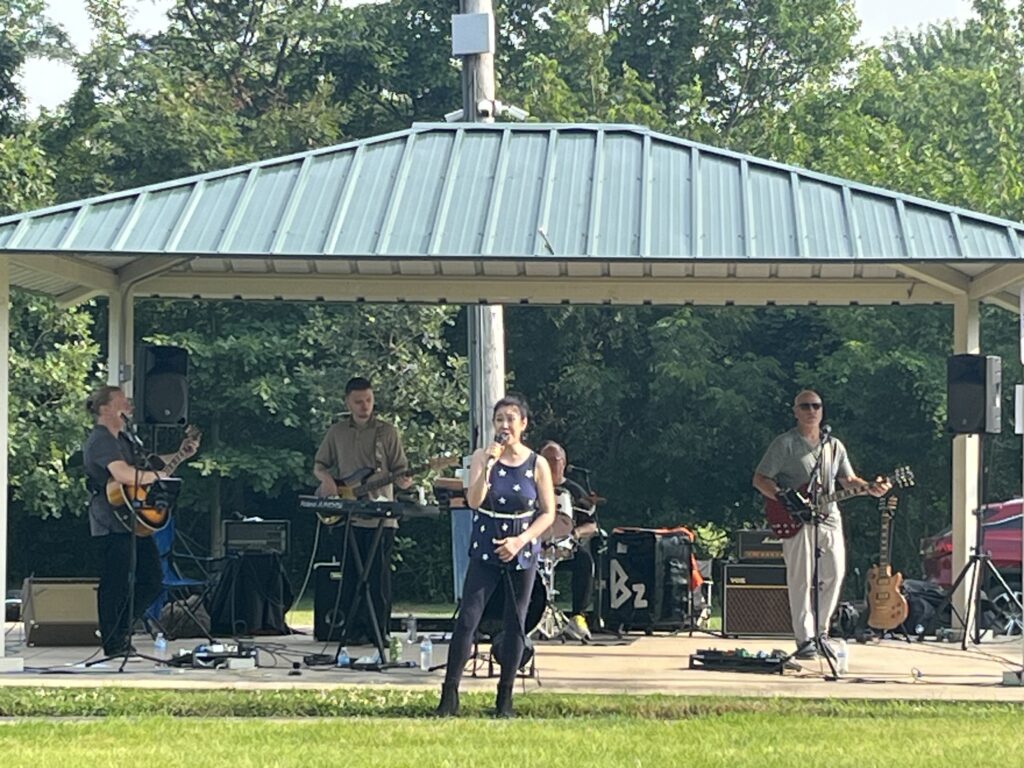 people in a band playing instruments in a shelter at Music by the Lake